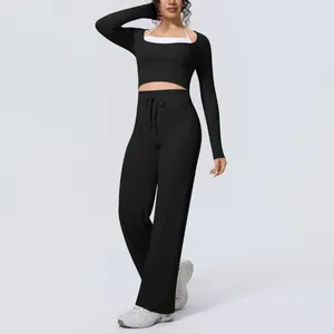 Professional studio shot of woman wearing black long sleeve yoga set with wide leg trousers