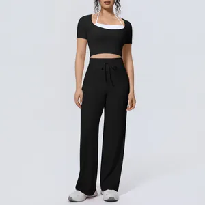 Women's two-piece sports yoga set with black short sleeve top and wide leg pants.