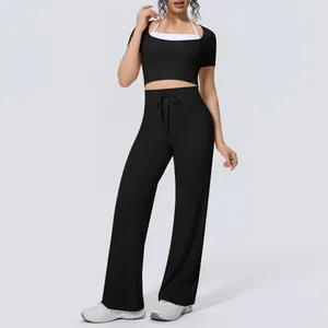 Full-body shot of model in black yoga set with halter neck top and wide-leg pants