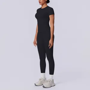 Seitenansicht einer Frau in einem schwarzen nahtlosen Kurzarm-Oberteil und Yoga-Leggings.