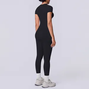 Seitenansicht einer Frau im schwarzen nahtlosen kurzärmeligen Yoga-Set mit Leggings