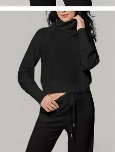Elegante mujer vestida con conjunto deportivo negro de punto gofrado y joggers.