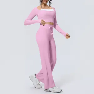 Full body view of a woman wearing a pink yoga set with long sleeve top and wide pants
