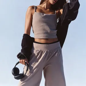 Close-up of stylish beige yoga set with thin strap camisole and wide-leg sports pants