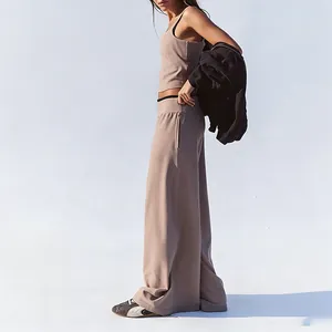 Side view of a beige wide-leg yoga trousers and matching tank top set on a model
