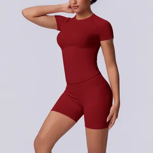 Model draagt een naadloze rode yoga-set met korte mouwen en een korte broek met hoge taille.