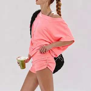 Close-up detail of a vibrant pink off-shoulder fitness set with ruched mini sports shorts