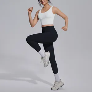 Full body view of a sporty woman in a white sports bra and black yoga leggings in a running pose