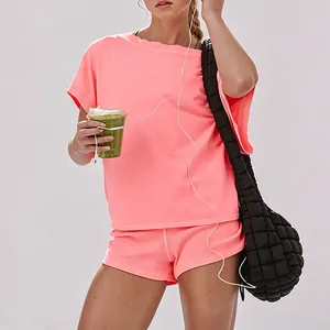 Close-up detail shot of coral athletic set featuring off-shoulder tee and gym shorts