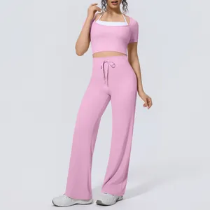 Full view of women's pink two-piece yoga set with crop top and wide-leg workout pants