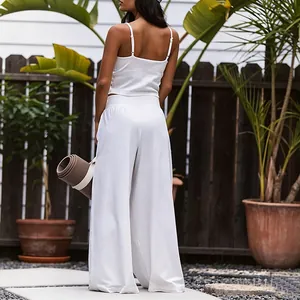 Back view of a woman wearing a white yoga camisole and wide-leg trousers outdoors