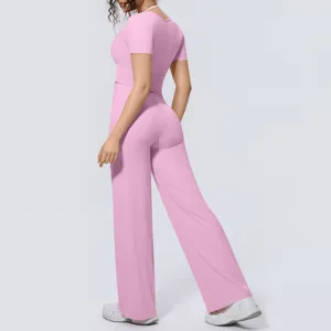 Back view of woman in a pink two-piece yoga outfit with crop top and wide-leg trousers