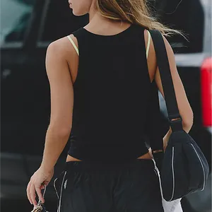 Back view of a slim-fit black ribbed tank top styled with sporty shorts and a sling bag