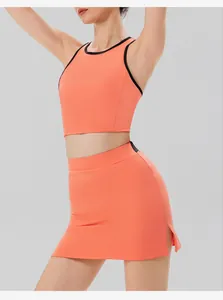 Detailansicht des korallenorangen Sportsets mit schwarzem Rand und kurzem Schlitzrock