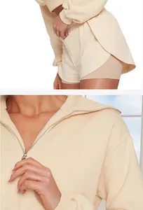 Détail d'un ensemble composé d'un sweat à demi-zip crème et d'un short de sport superposé