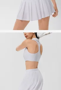 Dettaglio del set da tennis bianco con gonna a pieghe e reggiseno sportivo da donna