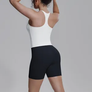 Achteraanzicht van een vrouw in witte racerback sporttop en zwarte yoga shorts set