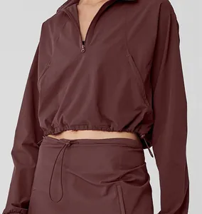 Close-up detail of the half-zip athletic sweatshirt and matching drawstring skirt in burgundy