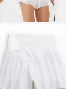 Gros plan sur un short de yoga blanc taille haute avec détail d'ourlet brodé festonné