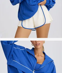 Close-up view of women's half-zip blue sports jacket and matching cream shorts outfit