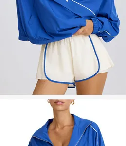 Close-up detail of women's blue half-zip sports jacket and white athletic shorts with piping