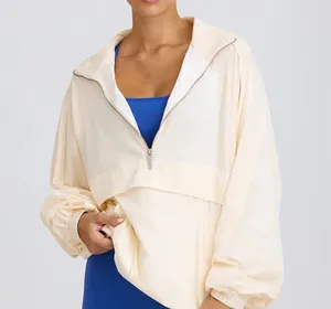 Detail view of a cream half-zip sports jacket with a stand-up collar for women.