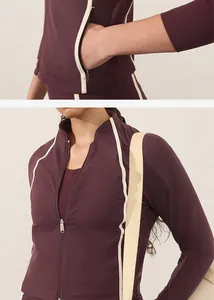 Detailed view of women's burgundy yoga jacket featuring a zipper and white piping accents