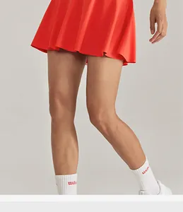 Détail d'une jupe de tennis rouge plissée avec des chaussettes de sport blanches.