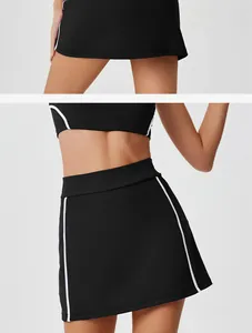 Detail view of black high-waisted tennis skirt featuring white piping and athletic fit