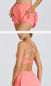 Detalle de pantalones cortos de yoga plisados color coral con cintura alta y secado rápido.