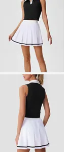 Detalle de falda de tenis plisada blanca y top corto de polo negro sin mangas