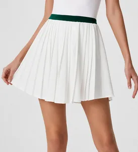 Close-up of white pleated tennis skirt with dark green contrast high waistband