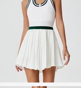 Close-up detail of white pleated tennis dress featuring green and black contrast waistband