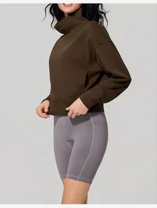 Side view of woman wearing a dark brown high neck sweatshirt and grey cycling shorts