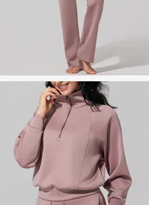 Detail of women's half-zip pink sweatshirt and matching high-waist athletic pants.