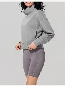 Side view of woman in grey funnel neck sweatshirt and purple biker shorts for sports