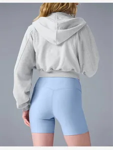 Back view of a cropped grey zip-up hoodie paired with light blue biker shorts
