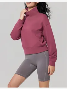 Detail view of a woman wearing a mauve stand-collar sweatshirt and grey athletic shorts