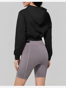 Back view of a women's black short hooded sports sweatshirt and gray biker shorts.