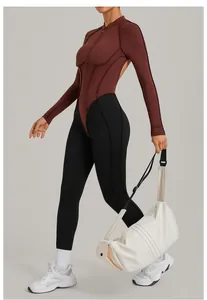 Body de sport à manches longues et dos nu, design color-block, porté avec un sac de sport blanc.