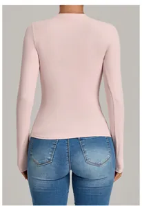 Back view of a slim fit light pink long-sleeve yoga top showing body contouring detail