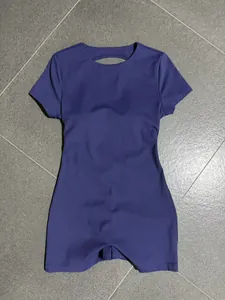 Back view of a purple short-sleeve backless yoga jumpsuit flat lay on grey floor.