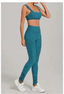 Side view of woman in teal heathered yoga bra and leggings set with snap hem details