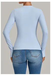 Back view of a light blue slim-fit long-sleeve yoga top paired with stylish denim jeans.