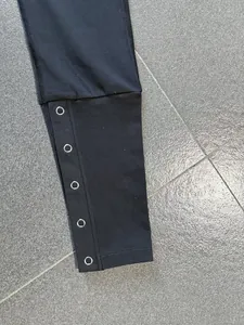 Detailansicht der schwarzen Yoga-Schlaghose mit hohem Bund und silbernen Druckknöpfen