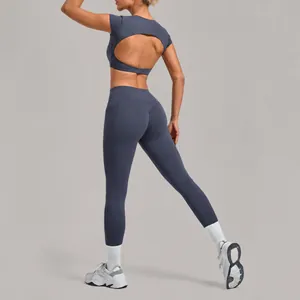 Two-piece greyish-blue yoga set with open back crop top and high-waisted leggings.