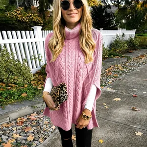 Detail van roze kabelgebreide coltrui poncho met stijlvolle zijsplitdetails