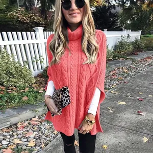 Modefoto van koraalkleurige kabelgebreide poncho met coltrui voor buiten