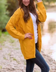 Vista detallada de un cárdigan de punto trenzado amarillo mostaza para mujer al aire libre