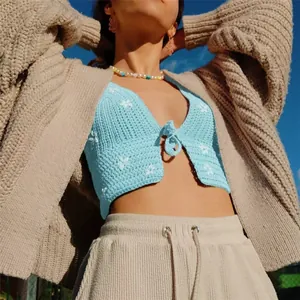 Vue détaillée d'un haut court en crochet bleu clair avec motifs floraux blancs et nœud